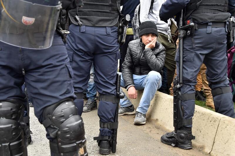 French riot police stand guard as migrants wait to be transported out of the Jungle migrant camp in Calais on October 24, 2016, the first day of a three-day operation to clear the camp before it is demolished. Philippe Huguen / AFP