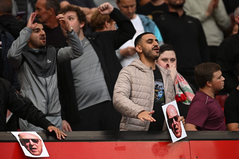 Liverpool fans hold pictures of Manchester United's owners and sing songs in their support. AFP