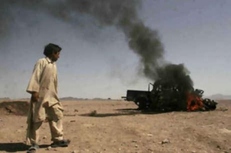 An Afghan boy look at police vehicle set on fire by protesters during a demonstration against the killing of civilian in an airstrike in Azizabad the village in Shindand district of Herat province, Afghanistan, Saturday, Aug 23, 2008. The U.S.-led coalition said Saturday that it would investigate allegations of civilian deaths during the battle.