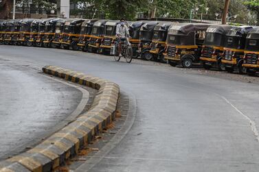 A man rides his bicycle near the parked autorickshaws along an almost deserted road in Mumbai. EPA