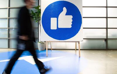 (FILES) In this file photo taken on October 23, 2019, a Facebook employee walks by a sign displaying the "like" sign at Facebook's corporate headquarters campus in Menlo Park, California. Social networking giant Facebook on December 16, 2020 opened fire on Apple, saying the iPhone maker's new measures on data collection and targeted ads will hurt small businesses. / AFP / Josh Edelson
