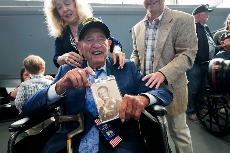 World War II veteran Joseph Eskenazi, who at 104 years and 11 months old is the oldest living veteran to survive the attack on Pearl Harbor, holds a photo of his younger self, at an event celebrating his upcoming 105th birthday at the National World War II Museum in New Orleans, Wednesday, Jan.  11, 2023.  (AP Photo / Gerald Herbert)