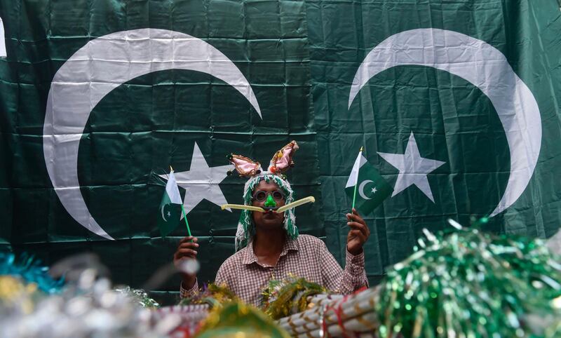 A street vendor holds Pakistani national flags as he waits for customers at a market in Lahore. AFP