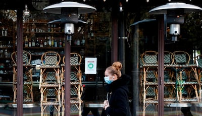 A woman walks past a closed restaurant in Paris on November 18, 2020, amid a second lockdown in France aimed at containing the spread of Covid-19 pandemic caused by the novel coronavirus. / AFP / THOMAS COEX
