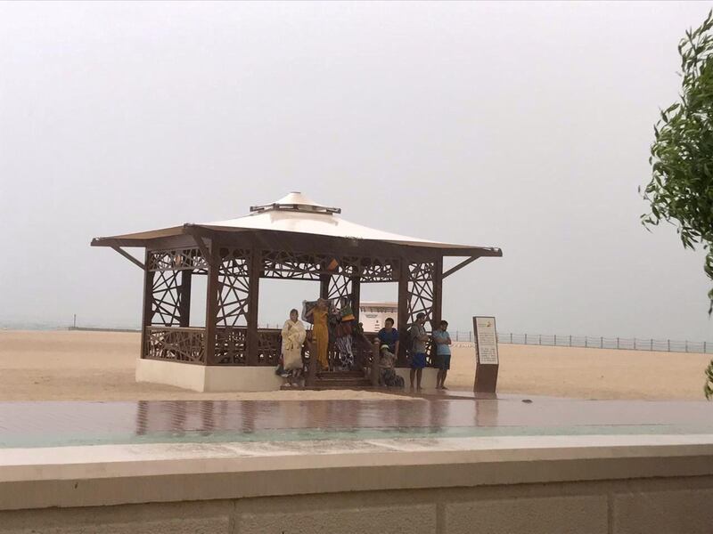 Beach goers sheltering from the rain. Leslie Pableo for The National