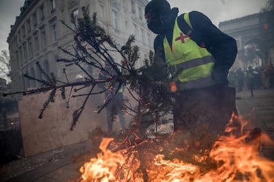 PARIS, FRANCE - DECEMBER 08: A protester carries a burning Christmas tree to a barricade during the 'yellow vests' demonstration near the Arc de Triomphe on December 8, 2018 in Paris France. ''Yellow Vests' ('Gilet Jaunes' or 'Vestes Jaunes') is a protest movement without political affiliation which was inspired by opposition to a new fuel tax. After a month of protests, which have wrecked parts of Paris and other French cities, there are fears the movement has been infiltrated by 'ultra-violent' protesters. Today's protest has involved at least 5,000 demonstrators gathering in the Parisian city centre with police having made over 200 arrests so far.  (Photo by Chris McGrath/Getty Images)