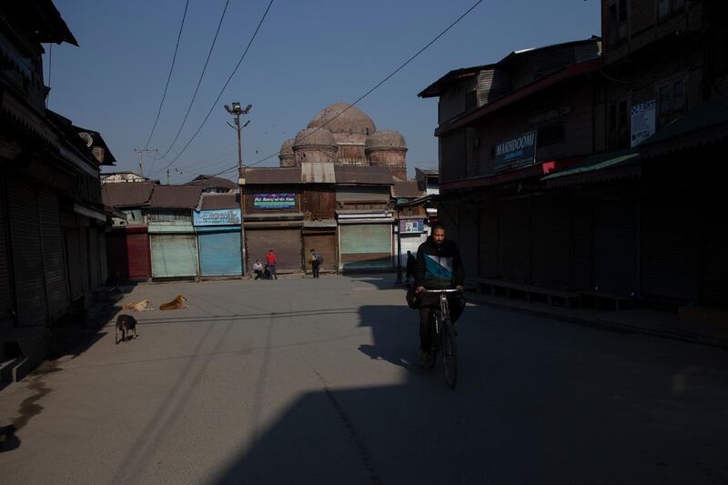 A Kashmiri cyclist rides through a closed market. AP Photo