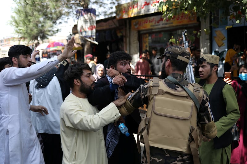 Afghan protesters speak to a Taliban fighter during the demonstration. Reuters