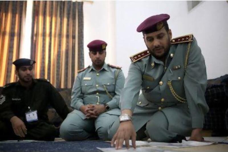 Civil Defence officers Mohammed al Braiki and Ali al Otaibi, and a soldier, explain a fire safety plan in a resident's home.