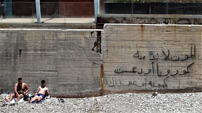 epa08514846 People rest after swimming next to a wall that reads in Arabic 'The death comes from Corona Covid-19, or from being run over by a truck, the same' during a sunny day at  Beirut sea coast, Lebanon, 28 June 2020. Lebanon has been seeing months of protests against the current government fueled by the dire state of the domestic economy. Many citizens fear that the combination of rising unemployment, poverty, sectarian tensions, the devaluation of the Lebanese pound, and the ongoing pandemic of the COVID-19 disease caused by the SARS-CoV-2 coronavirus, may spark another violent conflict, three decades after the end of the Middle Eastern nation's devastating civil war.  EPA/NABIL MOUNZER