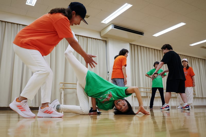 Seventy-one-year-old Reiko Maruyama, left, encourages Mieko Nanba, 68, as she practises a breakdance move known as a chair freeze during training with Ara Style Senior, Japan's only breakdancing club made up of elderly citizens, in Tokyo. Reuters