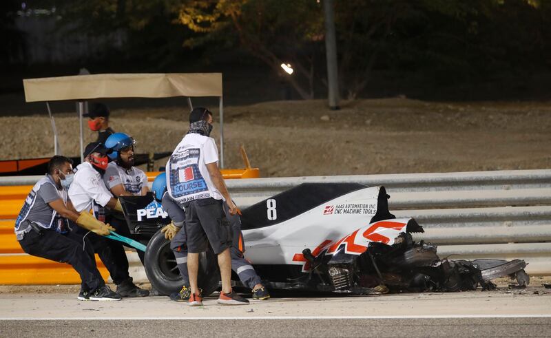 Stewards attempt to clear the car of Haas' Romain Grosjean from the track. Reuters