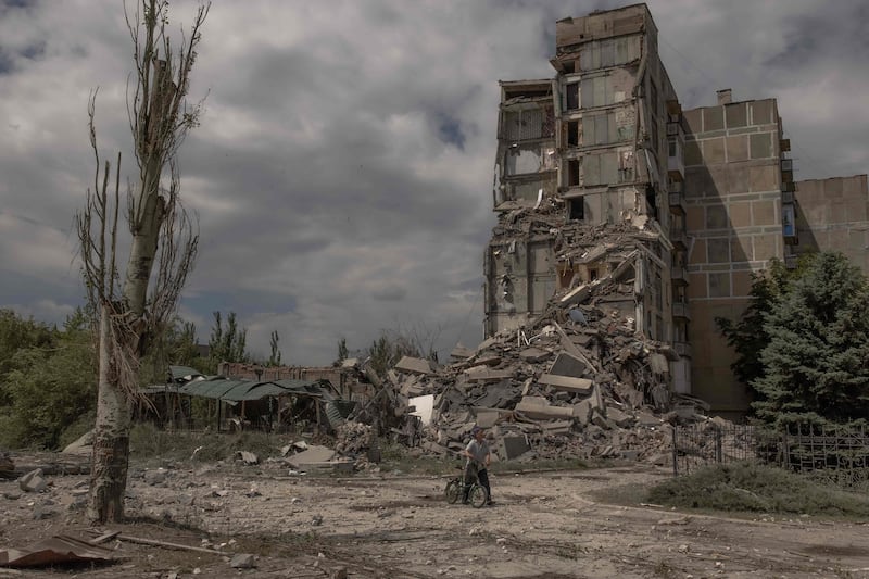 A resident pushes a bicycle past a destroyed building after shelling in Toretsk, eastern Donetsk. AFP