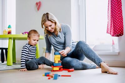 Smiling mother and toddler son playing with building blocks at home. Getty Images