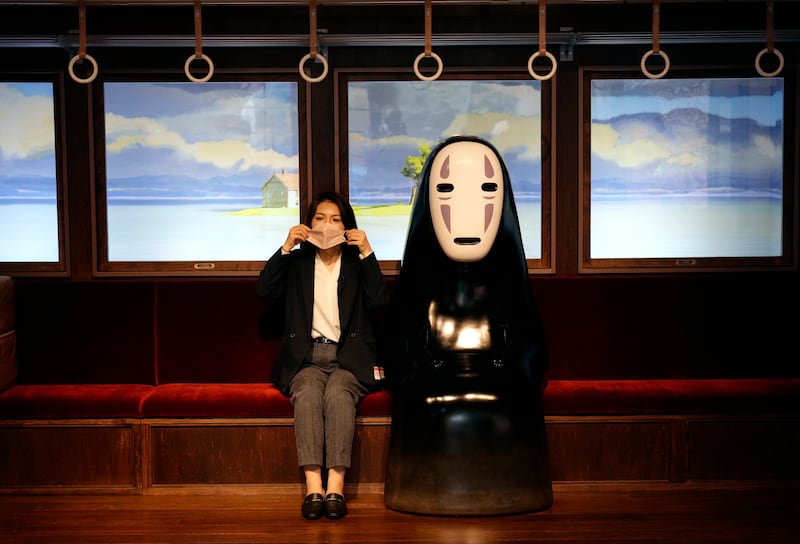 Sitting on a train next to the character No Face from 'Spirited Away' at Ghibli Park. EPA