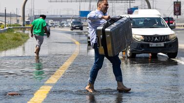 A man carries his luggage through floodwater caused by heavy rain on Sheikh Zayed Road in Dubai, in April 2024. AP