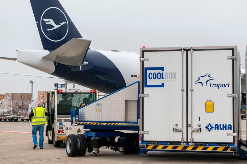 (FILES) This file photo taken on November 25, 2020 shows a vehicle transporting special cooling containers of airport operator Fraport to a Lufthansa Cargo aircraft at Frankfurt Airport, in Frankfurt am Main, western Germany. As German company BioNTech and other pharmaceutical companies leapt into action at the beginning of the year 2020 in search of the winning formula against the novel coronavirus, Germany's army of "Mittelstand" companies and other bigger manufacturing and logistics experts would soon prove crucial. / AFP / Thomas Lohnes
