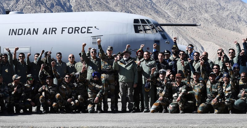 Mr Modi and the soldiers pose in front of a transport aircraft.