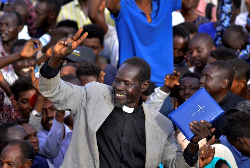 A Sudanese demonstrator holds the bible and chants slogans as he attends a sit-in protest outside the Defence Ministry in Khartoum. Reuters