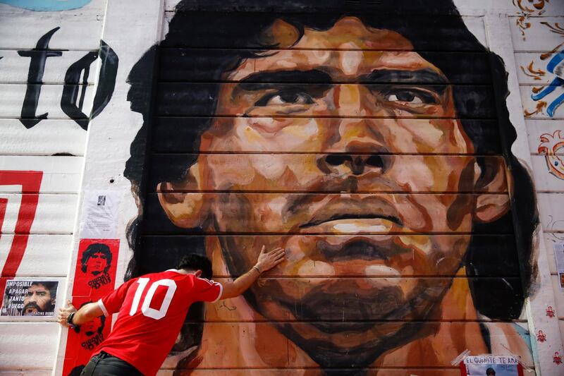 A boy touches a mural of Maradona outside the  Argentinos Juniors stadium. AP