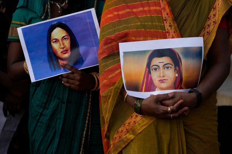 Women hold photographs of Indian educators and social reformers. AP