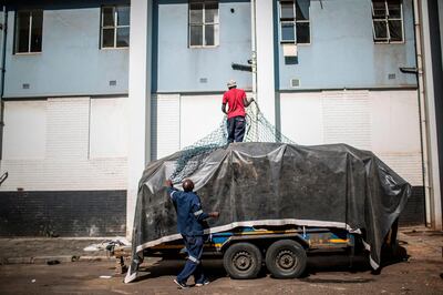 oMalayitsha (transporters) cover the trailer of goods with a tarp in central Johannesburg to be taken across the border to clients in Zimbabwe on February 20, 2019.  Items are loaded in Johannesburg onto trailers attached to minibuses which make the 550 kilometres (340 miles) journey north to the border of Zimbabwe, where economic situation has dramatically deteriorated, pushing inflation above 50 percent, and shortages of household essentials have become widespread. / AFP / GULSHAN KHAN 
