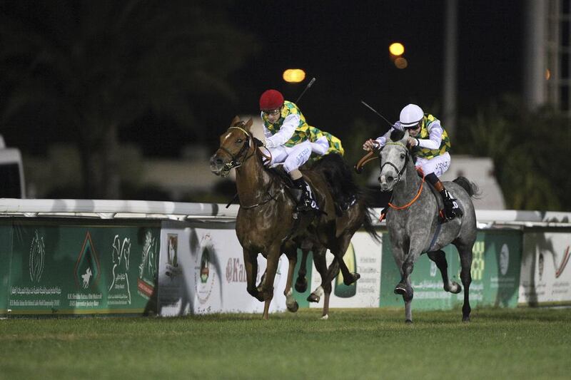 Rakha, left, ridden by Silvestre de Sousa, and Sha’Red, ridden by James Doyle, finished in a dead heat in the Al Ruwais sprint at the Abu Dhabi Equestrian Club on Sunday night. Lee Hoagland / The National

