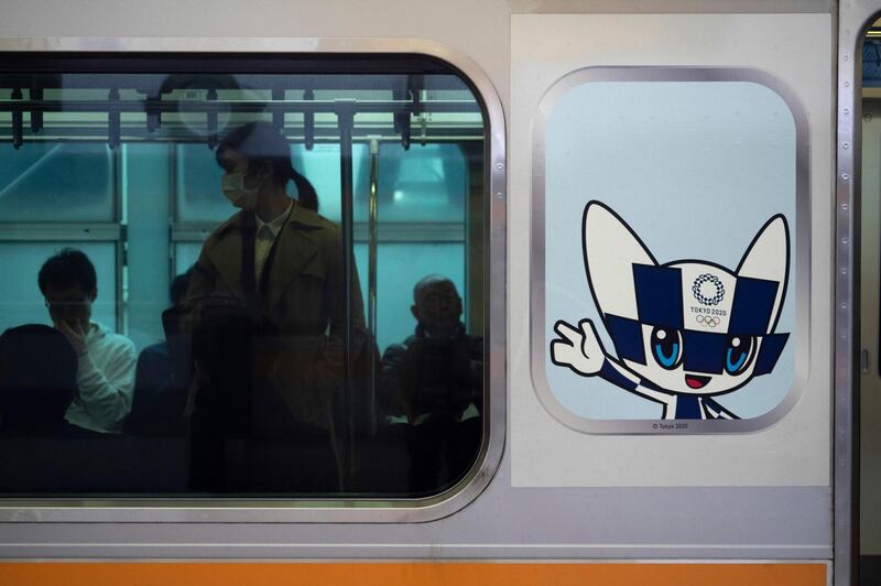 Commuters in a train carrying a poster showing the Tokyo 2020 Olympics mascot, Miraitowa, in Tokyo. AP