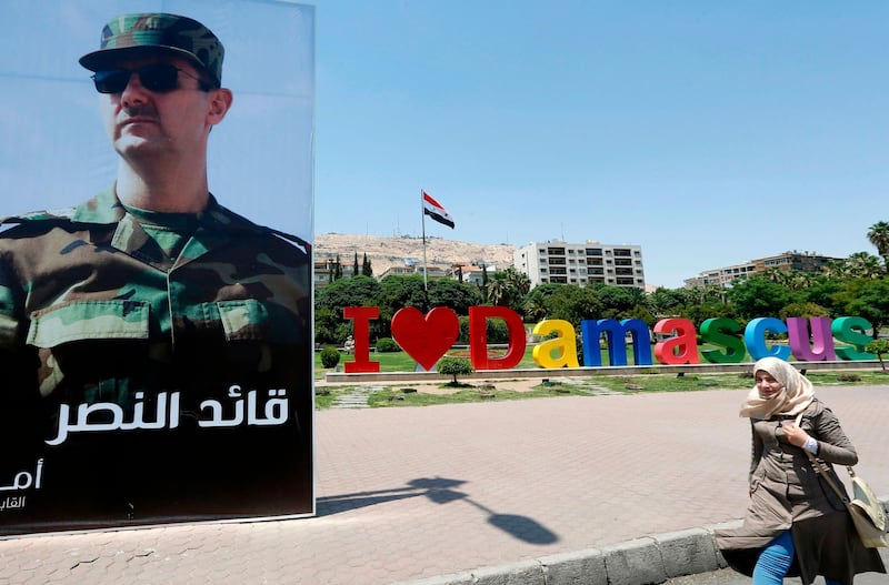 A Syrian woman walks past a poster of Syrian President Bashar al-Assad at the Umayyad Square in Damascus on June 6, 2018. / AFP / LOUAI BESHARA

