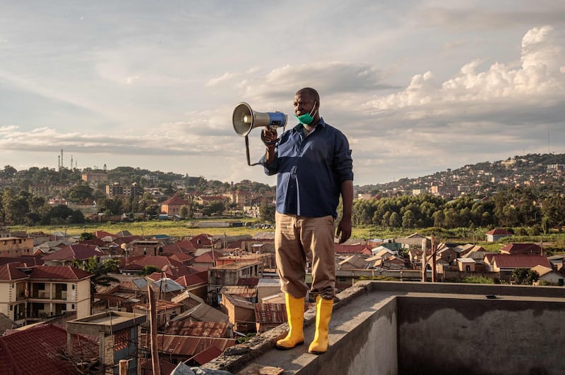 Gonzaga Yiga, a 49-year-old community chairperson, appeals to residents through a speaker from the tallest building of the area, in Kampala, Uganda.  AFP