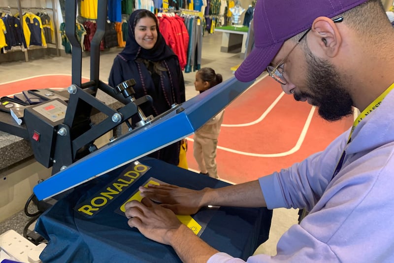 A staff member at Al Nassr club store prepares a t-shirt with Cristiano Ronaldo's name and famous jersey number 7 in Riyadh. AFP