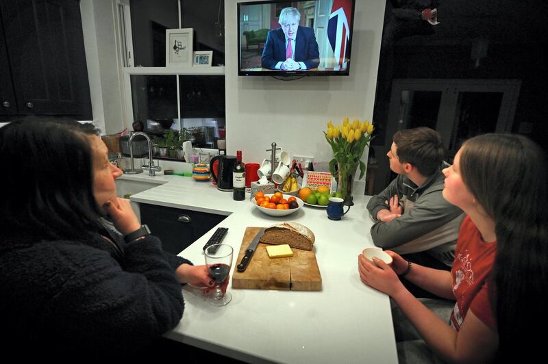 Members of a family listen as Britain's Prime Minister Boris Johnson makes a televised address to the nation from inside 10 Downing Street in London, with the latest instructions to stay at home to help contain the Covid-19 pandemic, from a house in Liverpool, north west England on March 23, 2020. - Britain on Monday ordered a three-week lockdown to tackle the spread of coronavirus, shutting "non-essential" shops and services, and banning gatherings of more than two people. "Stay at home," Prime Minister Boris Johnson said in a televised address to the nation, as he unveiled unprecedented peacetime measures after the death toll climbed to 335. (Photo by Paul ELLIS / AFP)