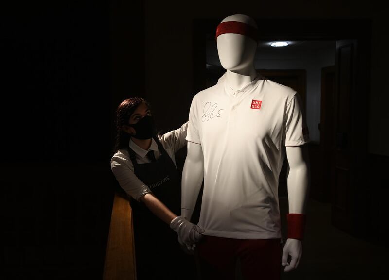 A Christie's employee poses with Swiss tennis Roger Federer's outfit used at the US Open 2018 at the Christie's auction house, in London.