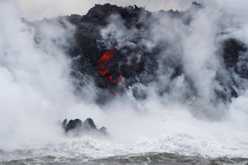 FILE - This May 20, 2018 file photo shows steam rising as lava flows into the ocean near Pahoa, Hawaii. White plumes of acid and extremely fine shards of glass billowed into the sky over Hawaii as molten rock from Kilauea volcano poured into the ocean, creating yet another hazard from an eruption that began more than two weeks ago: A toxic steam cloud. (AP Photo/Jae C. Hong, file)