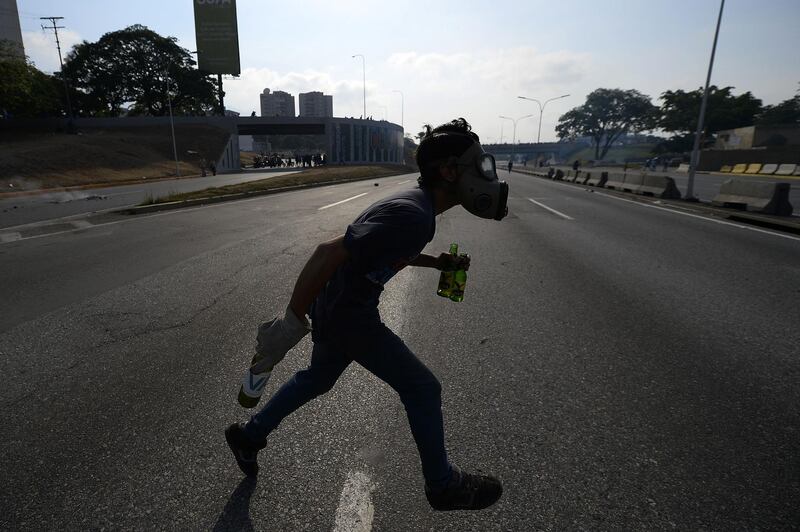 An opposition demonstrator runs during clashes with soldiers loyal to Mr. Maduro in front of La Carlota military base. AFP