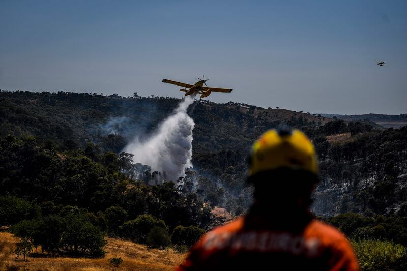A firefighter watches a plane drop water on a wildfire near Tavira, southern Portugal, on August 17. AFP