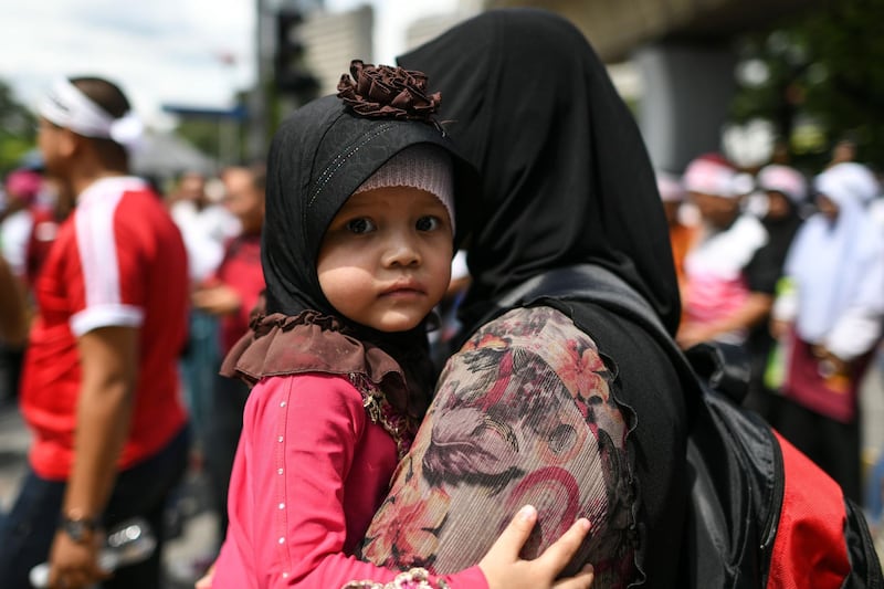 A mother carries her daughter during a rally organised by Muslim politicians against the signing of the UN anti-discrimination convention (ICERD) at Merdeka Square in Kuala Lumpur.   AFP