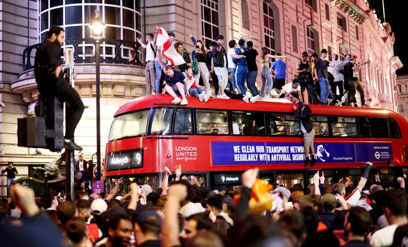 England fans celebrate on top of a bus at Piccadilly Circus.