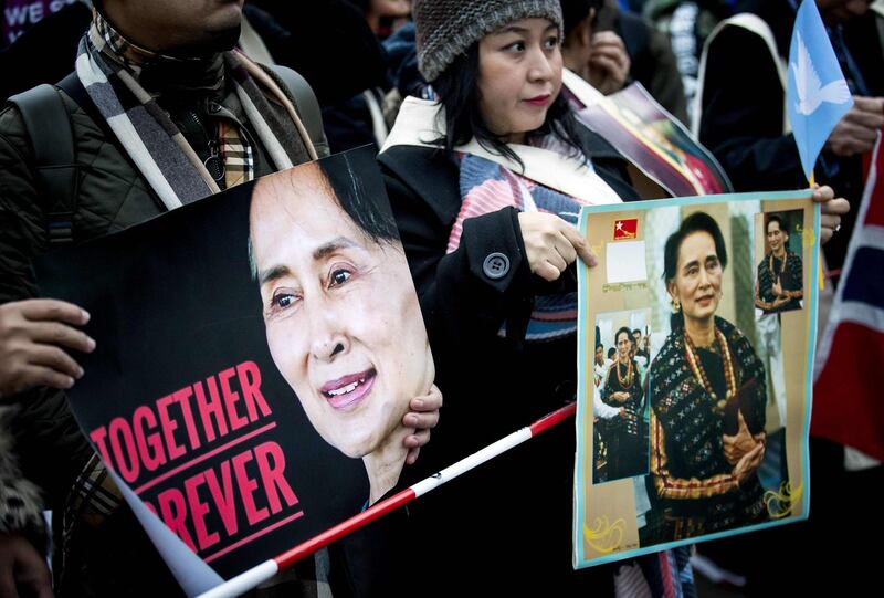 TOPSHOT - Protesters in support of Myanmar's State Counsellor Aung San Suu Kyi hold pictures in front of the Peace Palace of The Hague on December 11, 2019, following Aung San Suu Kyi's second day of hearing on the Rohingya genocide case. Aung San Suu Kyi is set to speak out in Myanmar's defence at the UN's top court on December 11, 2019, a day after the former democracy icon was urged to "stop the genocide" against Rohingya Muslims. Once hailed internationally for her defiance of Myanmar's junta, the Nobel peace laureate will this time be on the side of the southeast Asian nation's military when she takes the stand at the International Court of Justice. - Netherlands OUT
 / AFP / ANP / Koen Van WEEL
