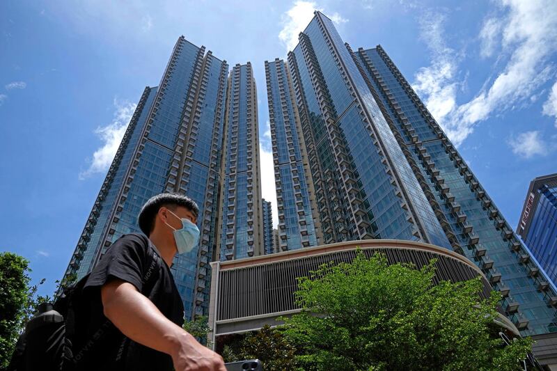 In this Tuesday, June 15, 2021, photo, a man walks in front of the Grand Central residential building complex where one of the HK$10.8 million (US$1.4 million) 449 square feet single-room flats will be offered as a prize in a lucky draw. Coronavirus vaccine incentives offered by Hong Kong companies, including a lucky draw for an apartment, a Tesla car and even gold bars, are helping boost the cityâ€™s sluggish inoculation rate. (AP Photo/Kin Cheung)