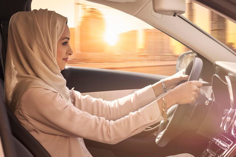 Emirati woman driving a car in Dubai at sunset. Getty Images
