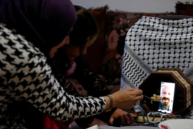 Palestinian Reem Abu Ayyash shows a spoon filled with rice during a video call with her husband Rami, a nurse who treats the coronavirus disease (COVID-19) patients and has avoided his family during Ramadan out of fear of contagion, as she prepares to have her Iftar (breaking fast) meal with her daughter at their home near Hebron in the Israeli-occupied West Bank April 28, 2020. Picture taken April 28, 2020. REUTERS/Mussa Qawasma TPX IMAGES OF THE DAY