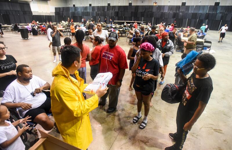 A Beaumont firefighter hands out blankets at the Beaumont Civic Center after the Center was opened as an emergency shelter Thursday morning, Sept. 19, 2019,  in downtown Beaumont, Texas, following flooding from Tropical Depression Imelda. (Ryan Welch/The Beaumont Enterprise via AP)