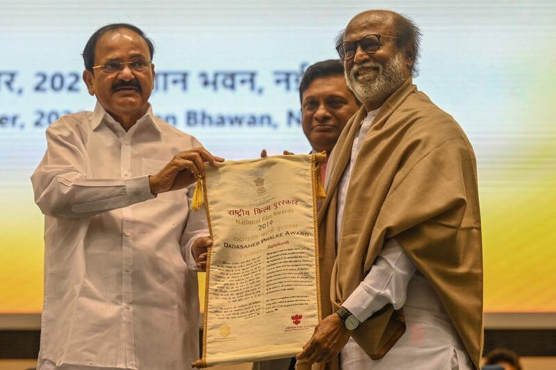 Actor Rajinikanth (R) receives the Dadasaheb Phalke Award from the Vice President of India Venkaiah Naidu, during the 67th National film awards and Dadasaheb Phalke Awards 2019 held in New Delhi on October 25, 2021.  (Photo by Money SHARMA  /  AFP)