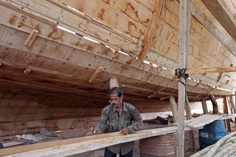 A shipbuilder works on a dhow at the boatyard.