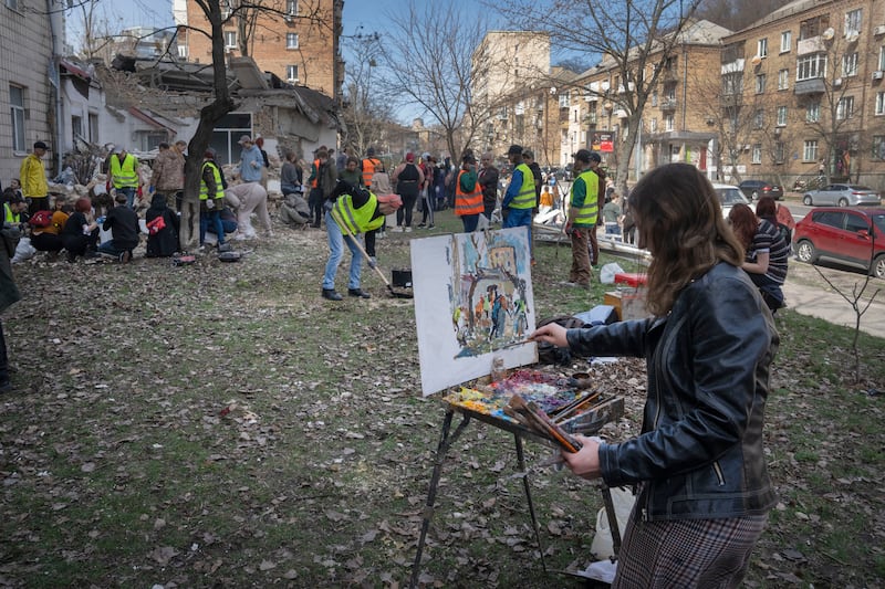A student of Kyiv State Arts Academy paints as other students clear rubble after the academy was partly ruined during the Russian missile in Kyiv, Ukraine. AP