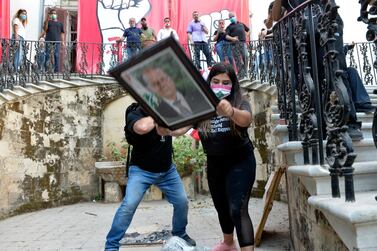 Protesters take down a picture of Lebanese President Michel Aoun as they enter the foreign ministry headquarters during a protest in Beirut, Lebanon. EPA