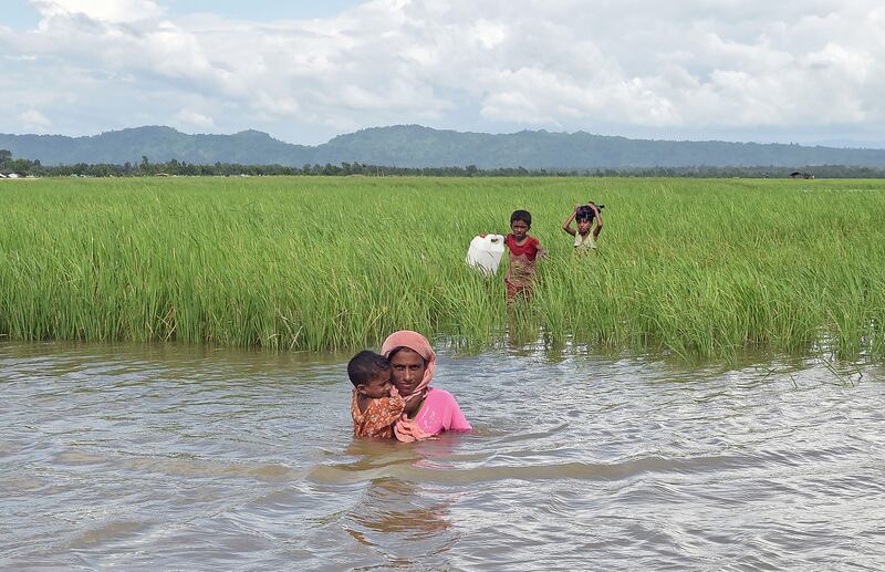 Rohingya refugee Khalida wades across a canal with her three children near the no man's land area between Bangladesh and Myanmar. Tauseef Mustafa / AFP Photo
