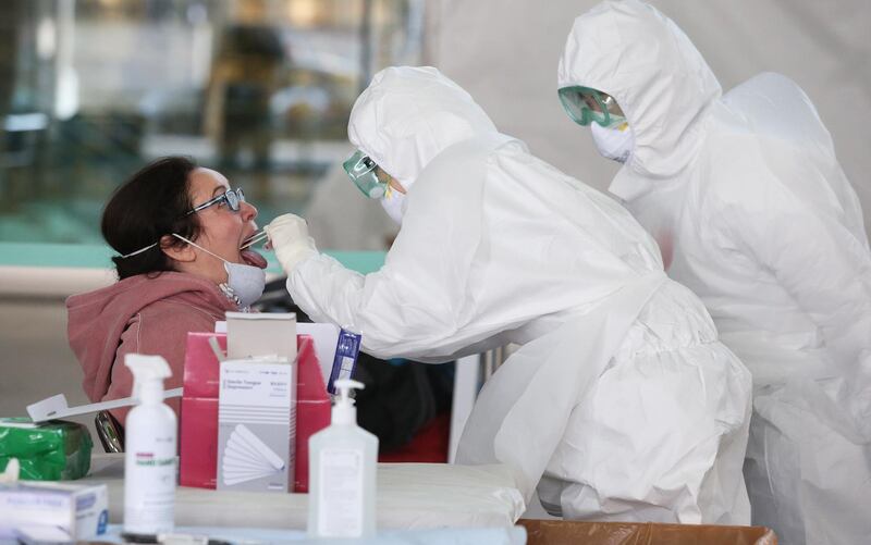 Medical workers wearing protective gear take samples from a foreign visitor at an 'Open Walking-Thru' centre for coronavirus Covid-19 tests at the airport in Incheon. EPA