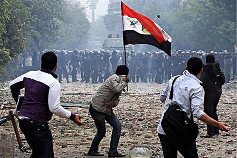 Youths confront security forces in Cairo yesterday. At least four people were killed and nearly 1,000 injured in the confrontations as protesters called for an end to military rule, but it was unclear if security forces had caused the deaths.